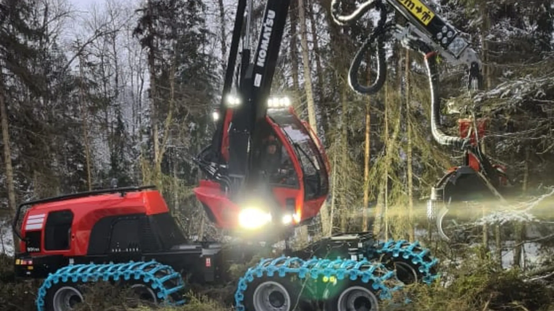 Skogsmaskin med tända arbetsljus i skogen